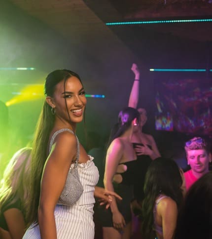 People enjoying a vibrant nightclub setting with colorful lights and lively atmosphere