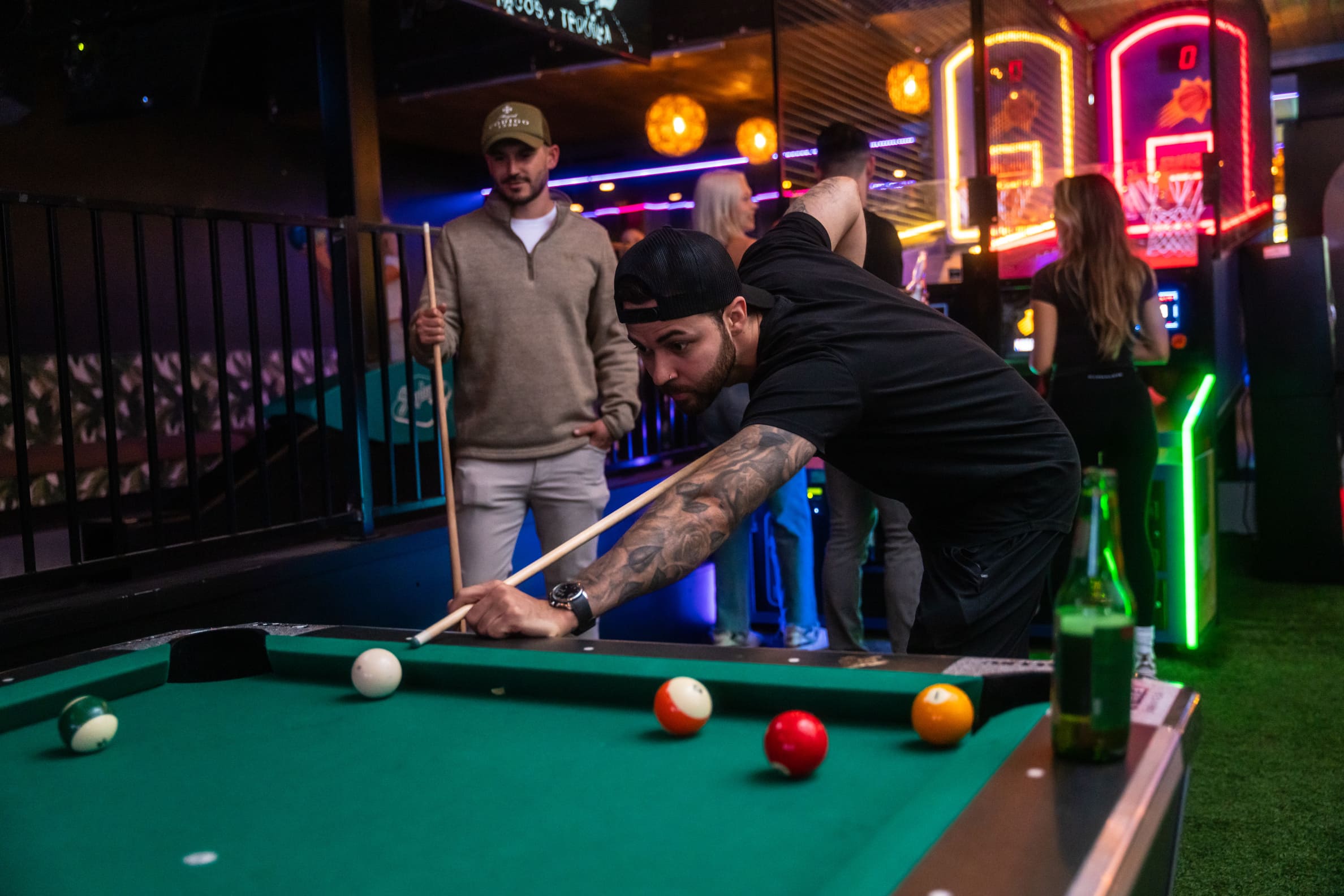 friends playing pool with an arcade background in Casa Amigos