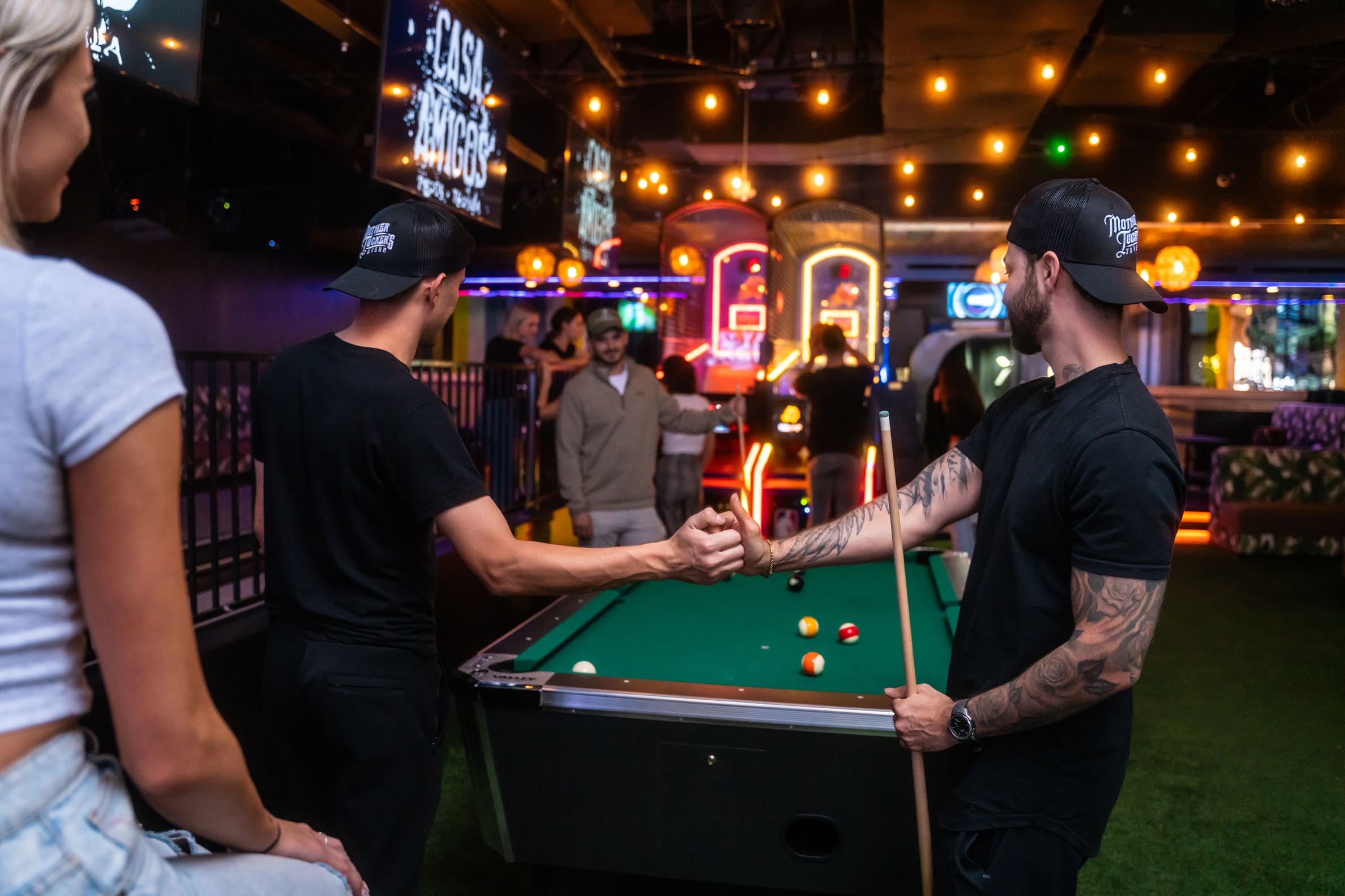 friends making a handshake by the pool table in Casa Amigos